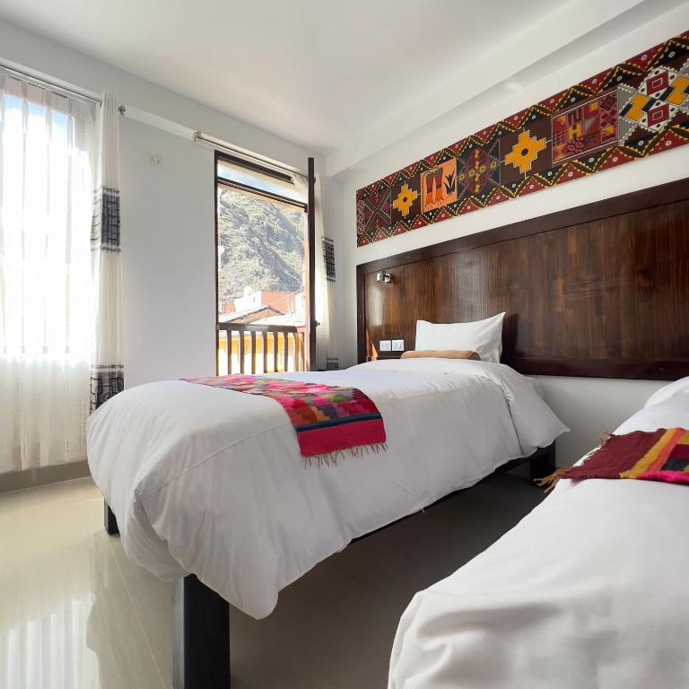 Habitación en Qata Inn con dos camas blancas, textil andino sobre el cabecero y vista a la montaña por la ventana